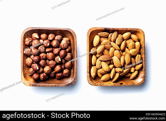 Peeled hazelnuts and almonds. Sweet nuts in wooden bowl isolated on white background