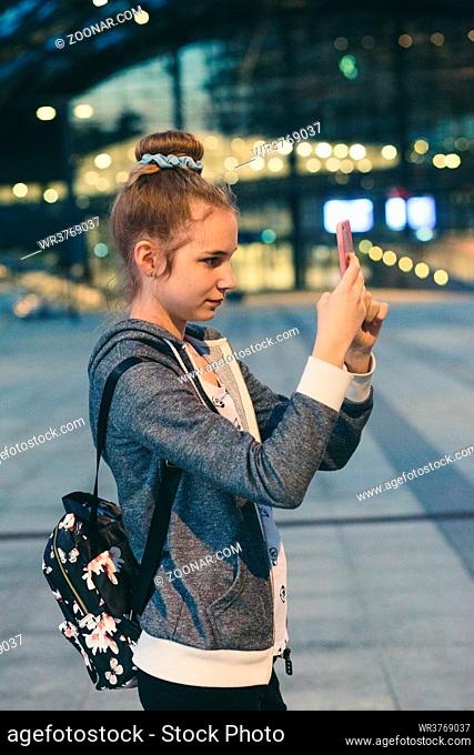 Young woman taking photos using a smartphone in the city at night