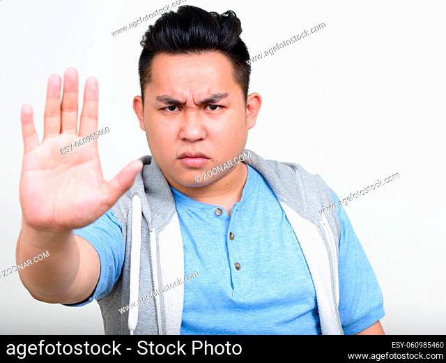 Studio shot of young handsome overweight Filipino man against white background