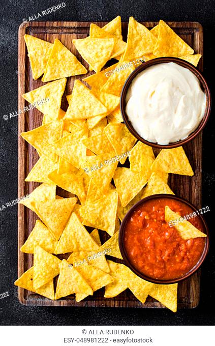Nachos corn chips with spicy tomato and cheese sauces. Mexican food concept. Yellow corn totopos chips with salsa sauce. Top view