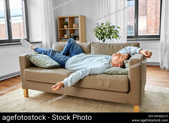 bored or lazy young man lying on sofa at home