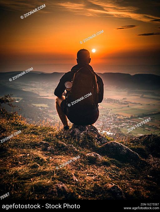 hiker relaxing on the mountain and watching sunset over the valley in austria hohe wand