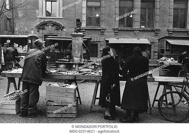 People shopping at the street market in piazza delle Erbe. Trento, December 1954