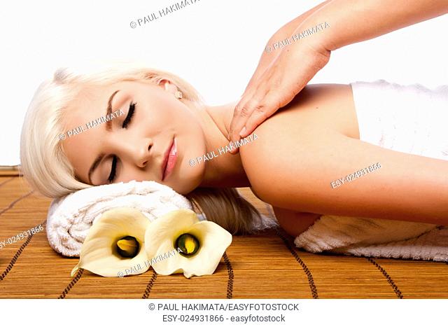 Beautiful young woman relaxing at spa getting therapeutic pampering shoulder massage