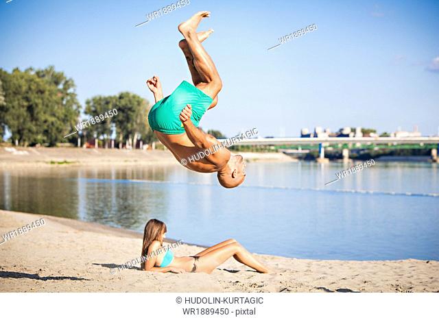 Young man somersaulting on the beach, Drava river, Osijek, Croatia