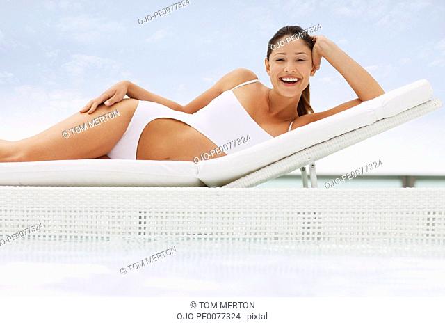 Woman in bathing suit laying on lounge chair at poolside