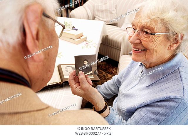 Senior woman showing her husband old photograph of herself