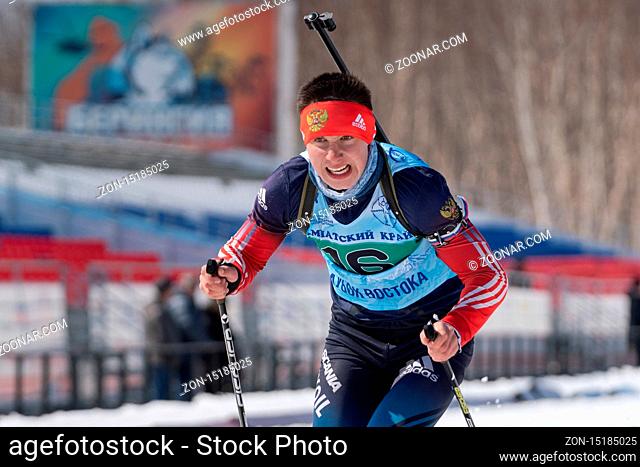 Kamchatka sportsman biathlete Aleksandr Kapustin skiing on ski track distance biathlon stadium. Junior biathlon competitions East of Cup