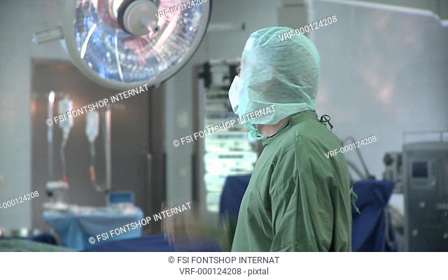 Medium shot lockdown of a doctor wearing surgical scrubs standing in an operating room