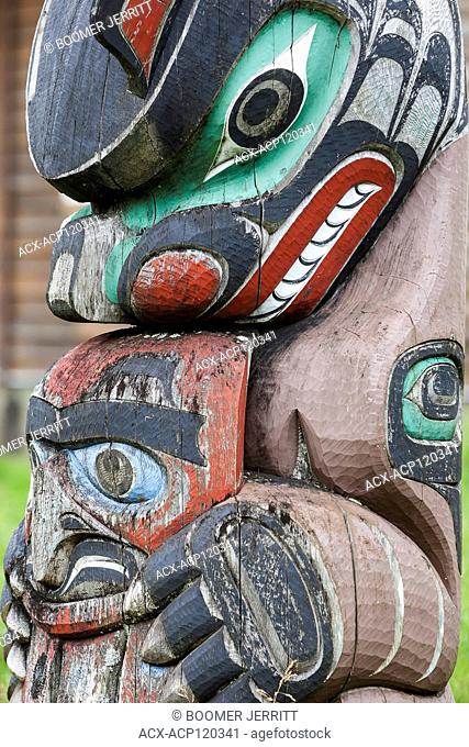 A weathered totem pole depicting Bear stands outside of a residence in the tiny village of Oweekeno. Rivers Inlet, British Columbia Central Coast, Canada
