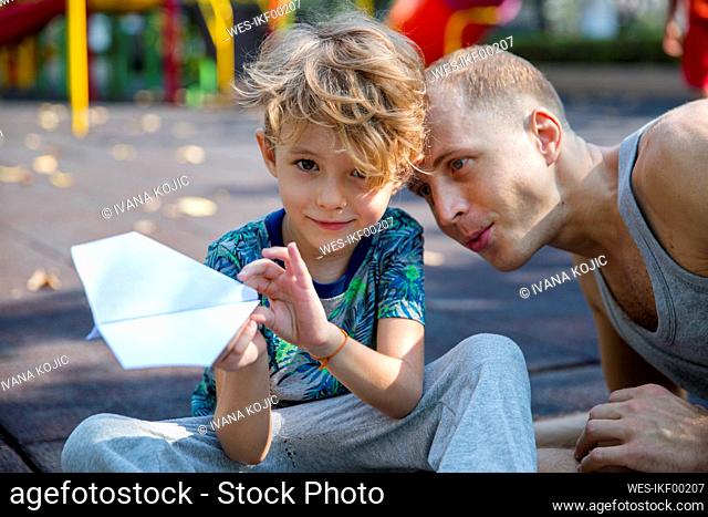 Father with smiling son holding paper airplane