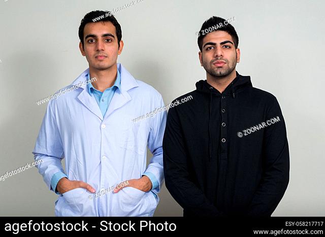 Studio shot of two young Indian men as doctor and patient together against white background