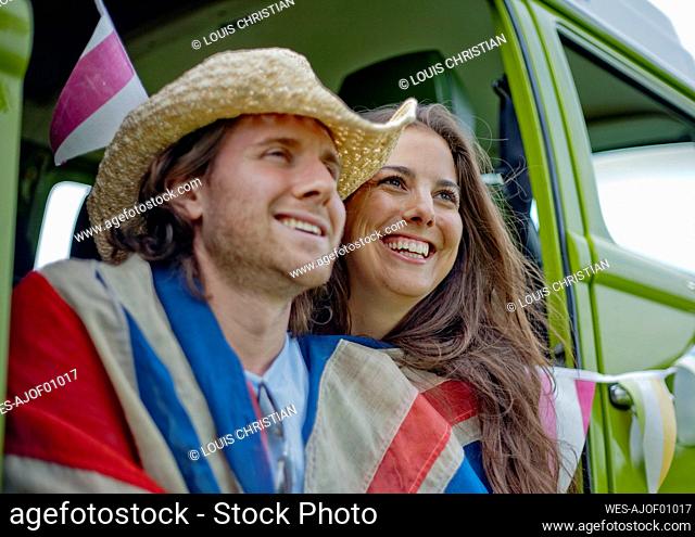 Smiling woman with boyfriend in camper van looking away
