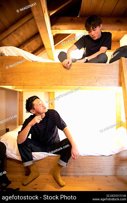 Young people sitting on bank bed in vacation rental