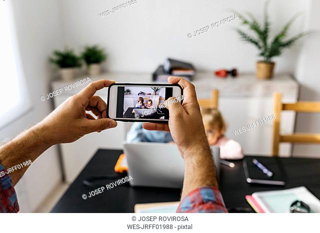 Father taking pictures of his children, using his laptop