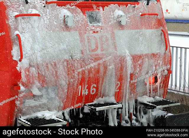 08 February 2021, Saxony-Anhalt, Magdeburg: A Deutsche Bahn electric locomotive with an icy front stands on the platform
