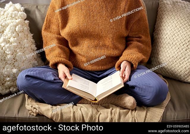 woman in warm sweater reading book at home