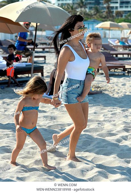 Kourtney Kardashian wears a white one piece swimsuit and denim hotpants as she takes her kids to the beach in Miami Featuring: Kourtney Kardashian, Reign Disick