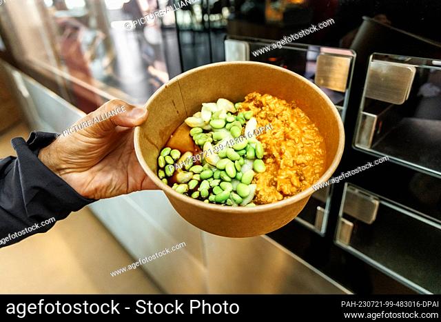 PRODUCTION - 20 July 2023, Schleswig-Holstein, Grömitz: A person holds a dish prepared by a cooking robot. The cooking robot can prepare five different dishes...
