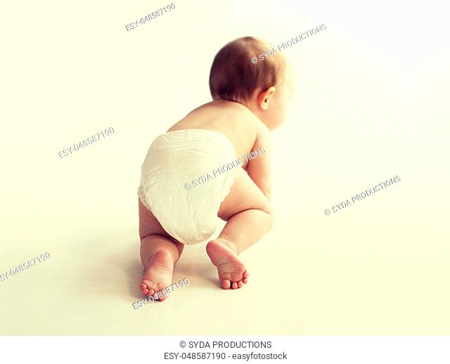 little baby in diaper crawling on white floor