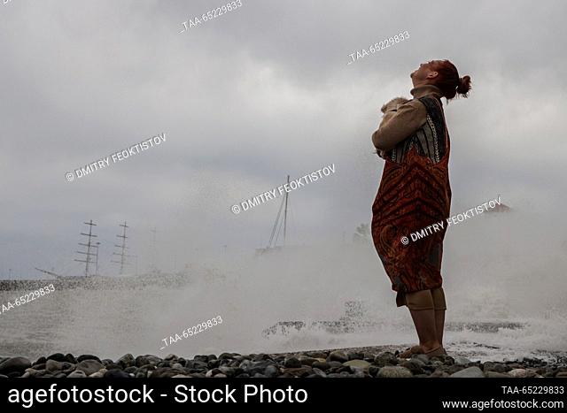 RUSSIA, SOCHI - NOVEMBER 26, 2023: A woman with a dog is seen on a beach as high winds and waves hit the resort of Sochi during a storm at Russia's Black Sea...