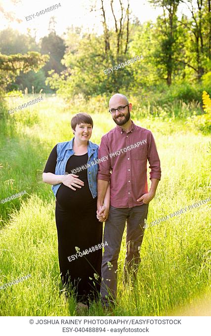 Man and a pregnant woman in a field in Oregon while the girl is in her third trimester. The couple is married and this husband and wife are expecting their...