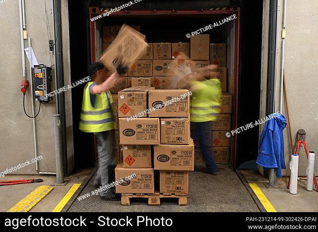 PRODUCTION - 14 December 2023, Bremen, Bremerhaven: Employees of the pyrotechnics company, Comet Feuerwerk GmbH, empty an overseas container filled to the...