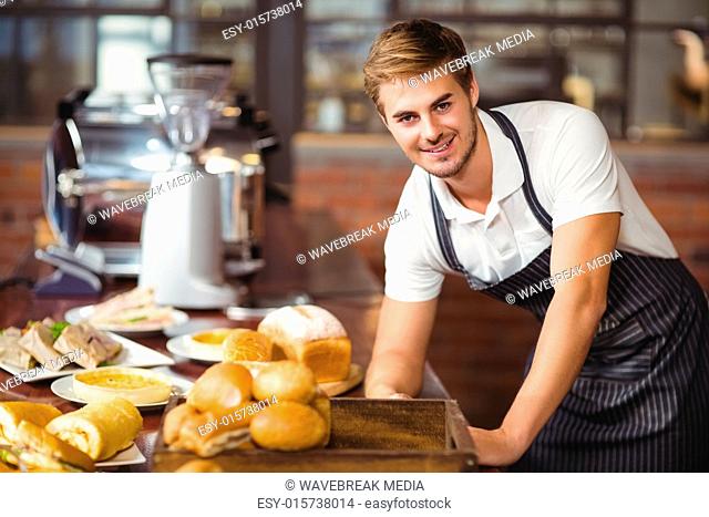 Handsome waiter leaning on a food table