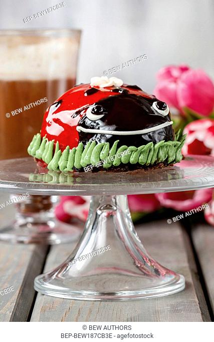 Ladybug cake and cup of hot chocolate in the background