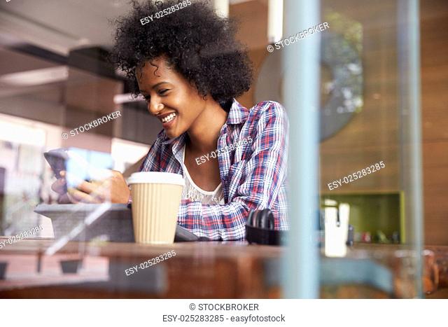Businesswoman On Phone Using Digital Tablet In Coffee Shop