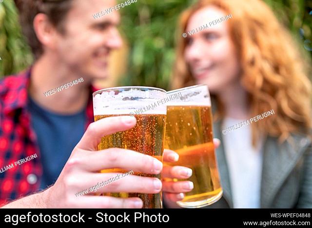 Man and woman toasting beer glasses at pub