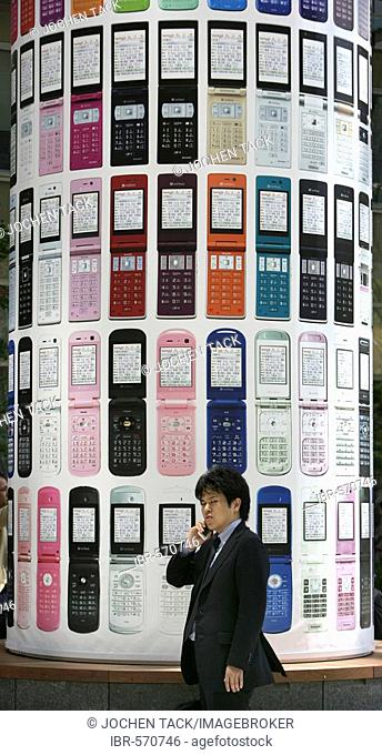 Asian businessman with mobile phone, advertising of Japanese provider Softbank, Tokyo, Japan