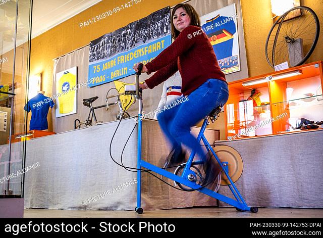 PRODUCTION - 28 March 2023, Mecklenburg-Western Pomerania, Malchow: Isabel Krukenberg rides a GDR-branded ""Germania"" exercise bike at the GDR Museum in the...