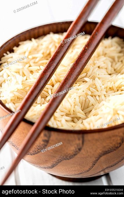 Uncooked indian long rice in bowl and chopsticks