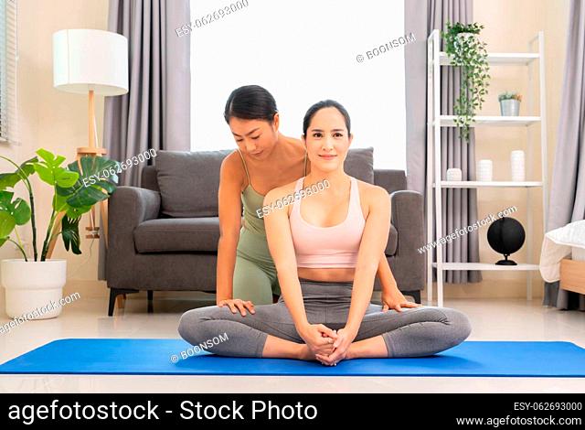 Young woman beginning yoga practice with private teacher at home. Professional instructor teaches student to do Baddha Konasana exercise or Butterfly pose