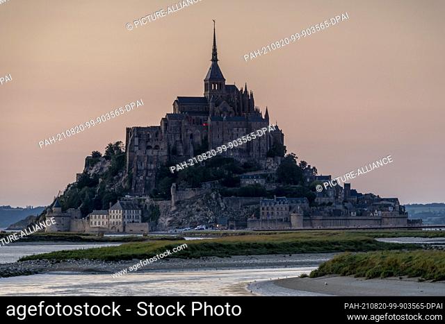 12 August 2021, France, Le Mont Saint Michel: Dusk at Mont Saint Michel. The rocky monastery island in the Normandy tidal flats is once again attracting...