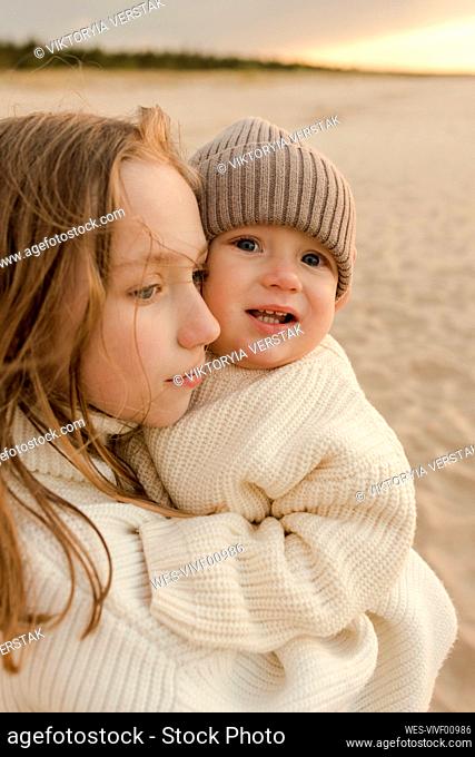Girl with baby brother at beach