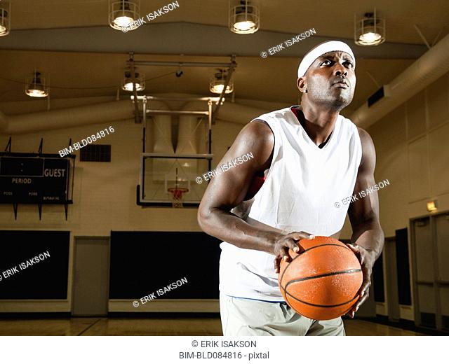 Black man shooting basketball on basketball court