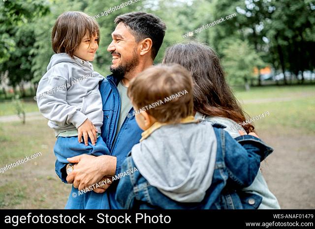 Happy father and mother enjoying with children in park