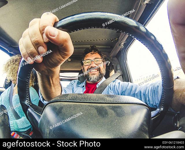 Concept of caucasian couple travel with car vehicle - inside wide view of man driver and woman passenger - happy people move with vehicle - adult friends enjoy...