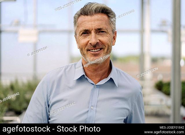 Close-up of smiling male professional standing in plant nursery
