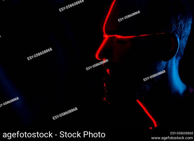 Man in dark with face illuminated by scan red laser on contour