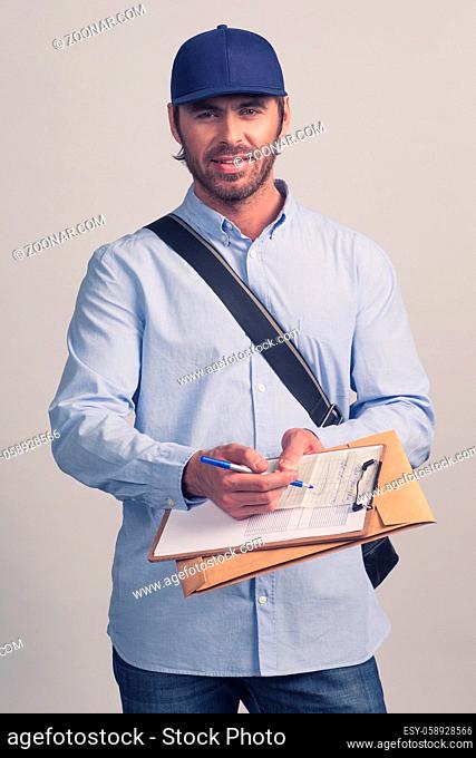 Man in blue uniform holding delivery form on clipboard for delivery
