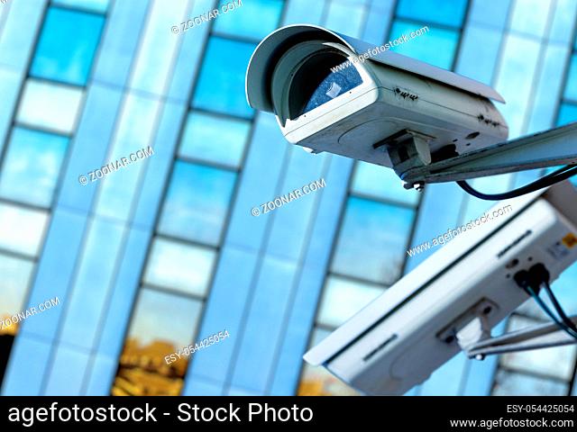 cctv security camera in a city with blury business building on background