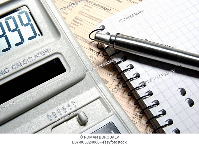 Calculator with numbers on display, pen and notebook laying on n