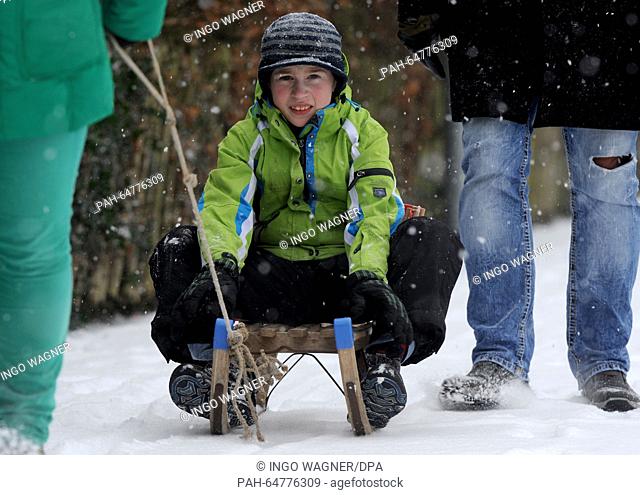 Student Robin Ebener plays with his parents while riding a sleigh on a street path in Ganderkesee, Germany, 03 January. After a mild December