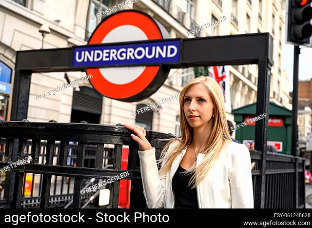 Close up portrait of an attractive smiling young woman with an underground station in the background in downtown London, United Kingdom
