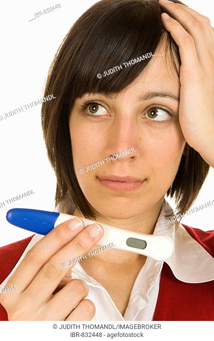 Worried 20-year-old woman holding a pregnancy test