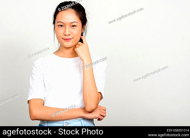 Studio shot of young beautiful Asian teenage girl against white background