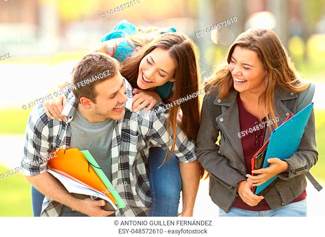 Three happy students and friends joking and laughing together in an university campus with a green background
